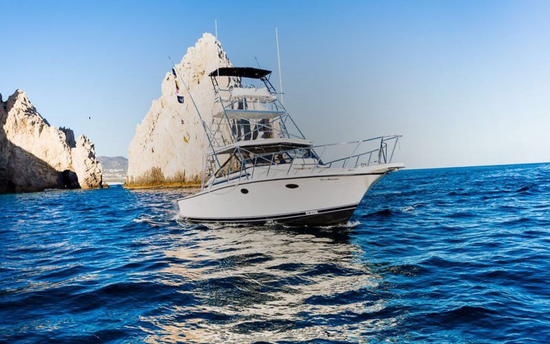 Sportfishing boat with outriggers cruising along the cliffs of Land's End