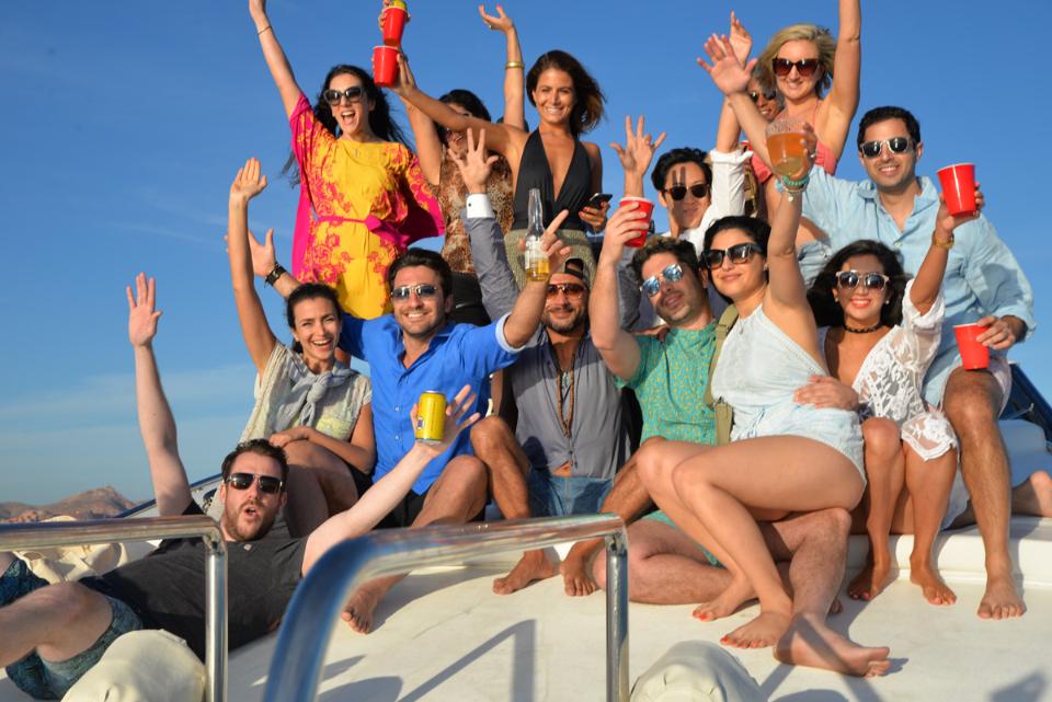Group of friends cheering on the bow of a yacht