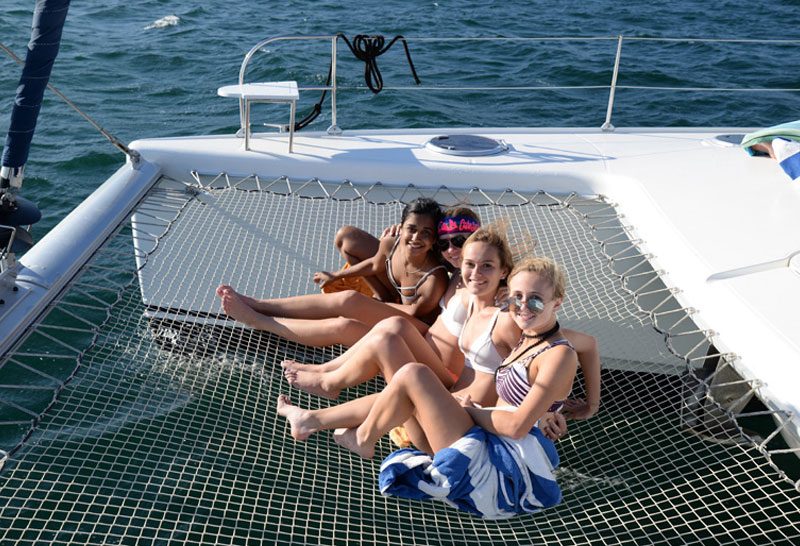 Friends relaxing on the trampoline nets of a catamaran