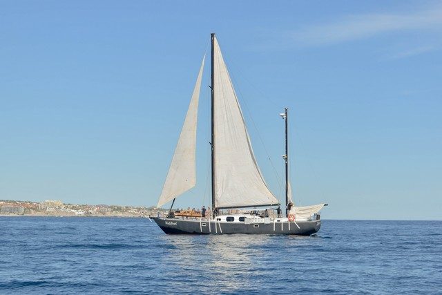 Classic sailboat under sail on calm blue water