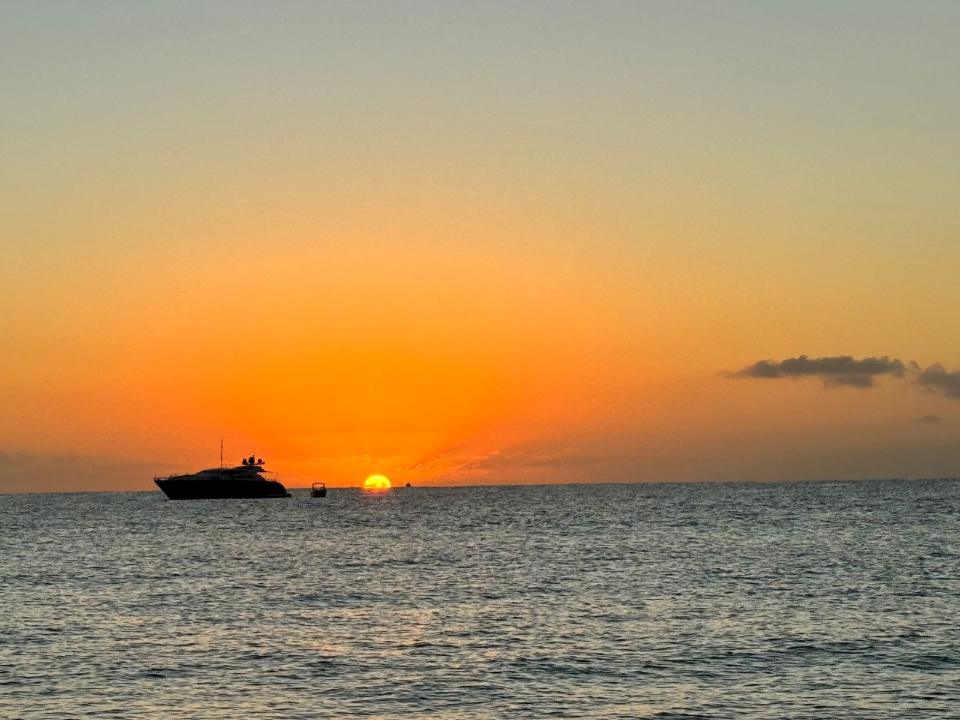 Yacht silhouetted against an orange sunset over the ocean
